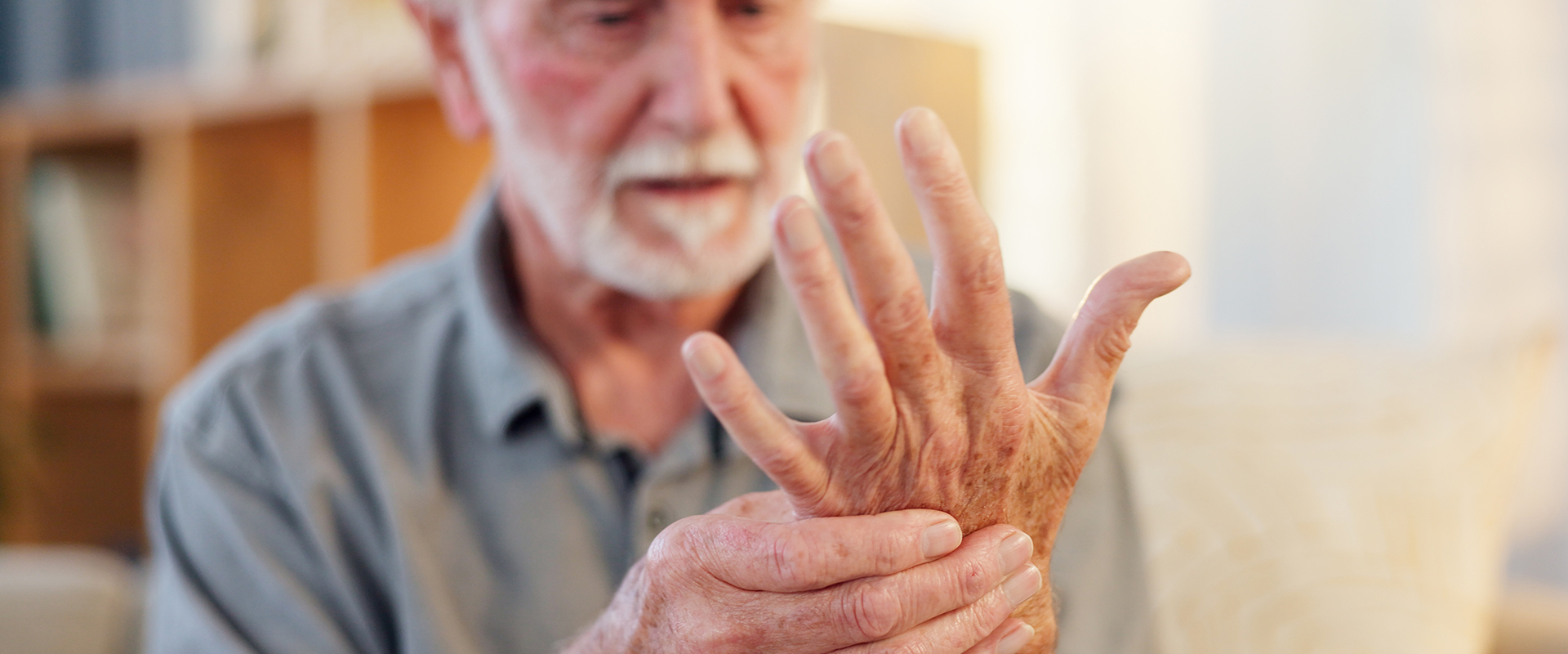Mann schaut seine schmerzende Hand an